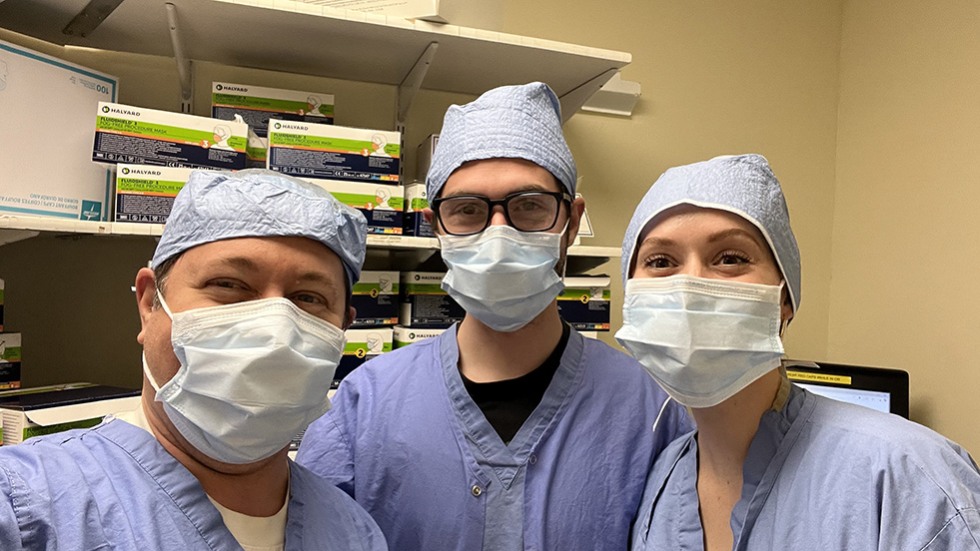three doctors in scrubs and PPE